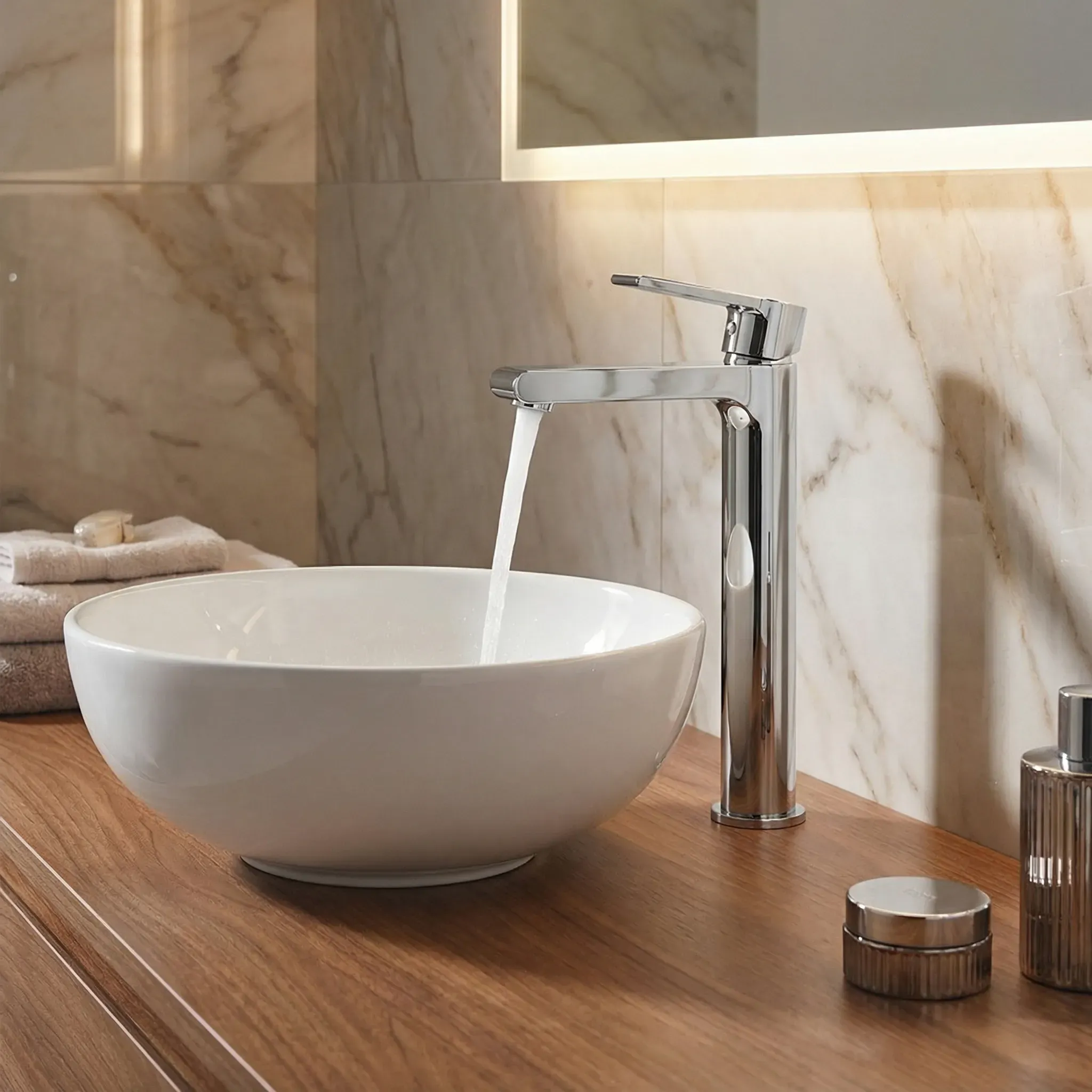 A sleek chrome faucet pours water into a white vessel sink on a wooden vanity.