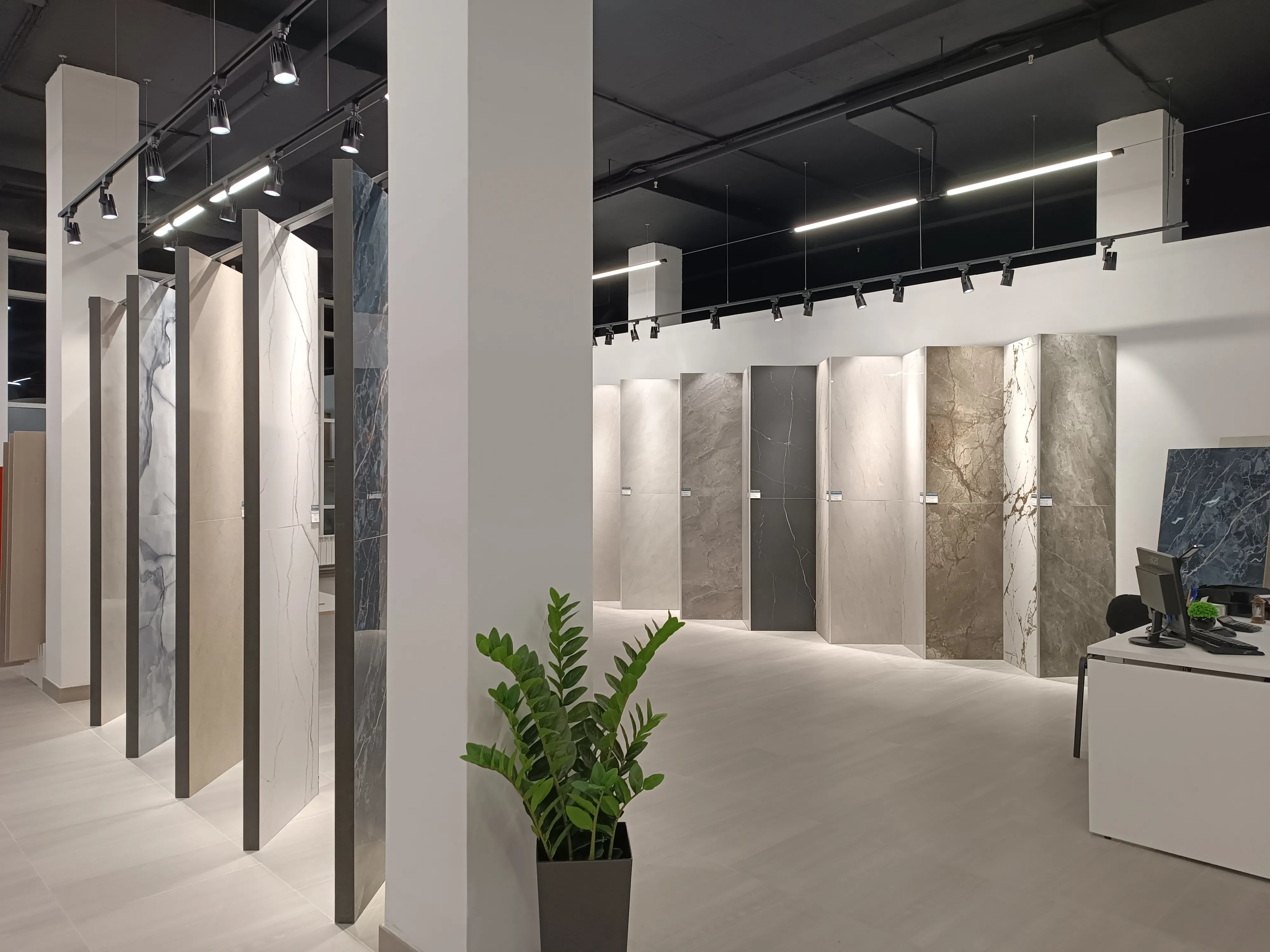 A modern showroom displays rows of large format tiles in various patterns and finishes.